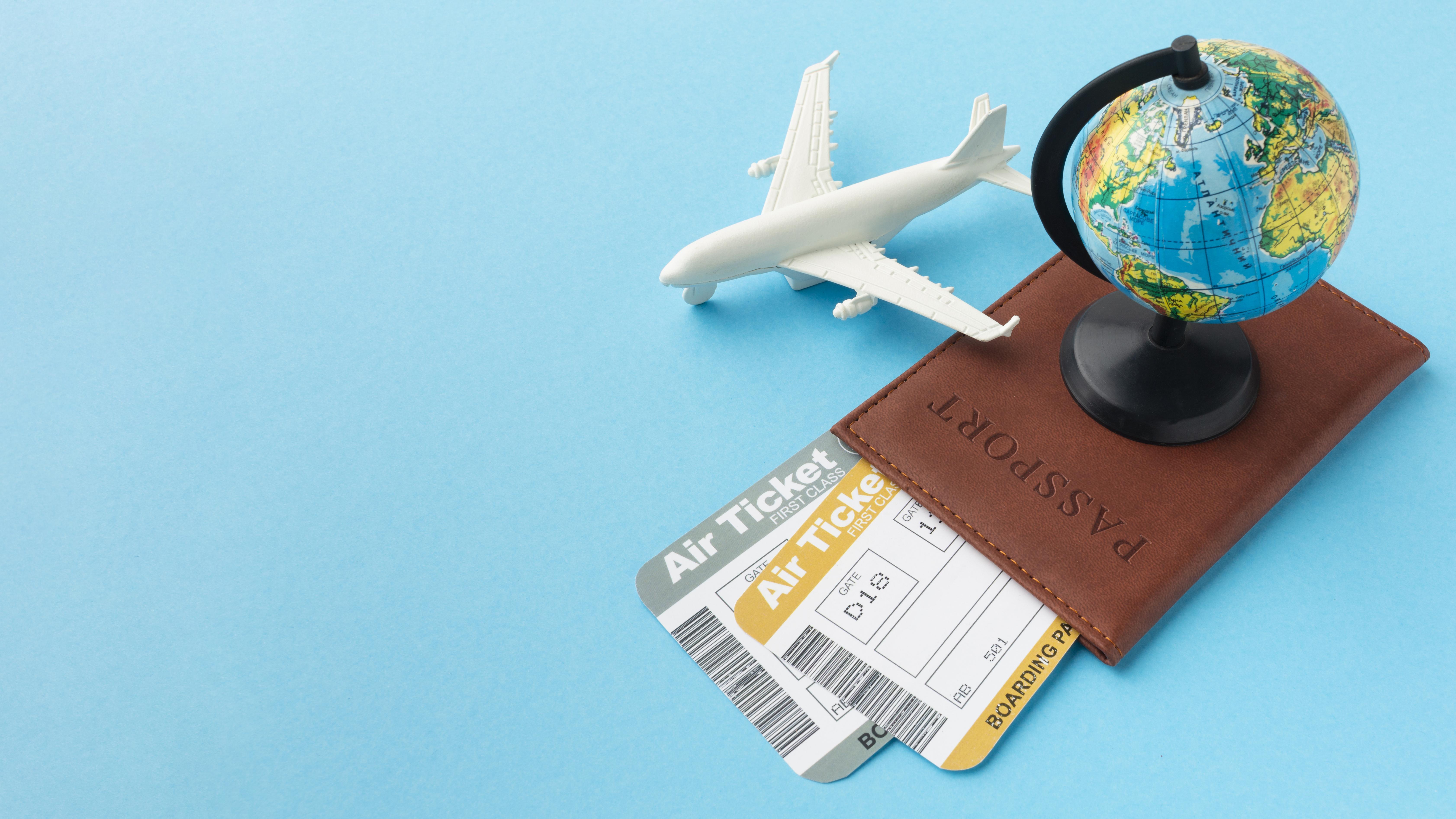 Miniature airplane, globe, and tickets on a passport against a light blue backdrop, conveying travel excitement and adventure planning.